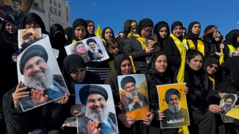 Reuters Women hold pictures depicting late Hezbollah leader Hassan Nasrallah