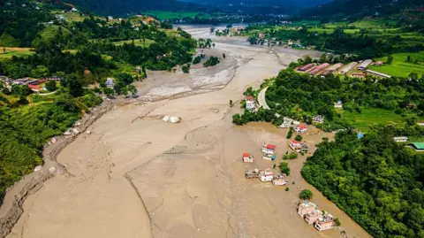 NurPhoto via Getty Images Aerial view shows flood-damaged areas after a flash flood swept through the Bhotekoshi River in Nuwakot, Nepal, on August 26, 2026.