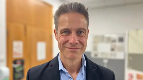 Dr Ben Noble smiles and looks into the camera at Coalville Community Hospital