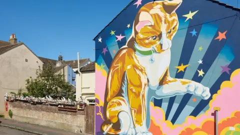 A colourful mural of a cat on the side of a house