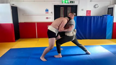 Nicholas sparring with his coach Scott Findlay wearing his sumo wrestling uniform.