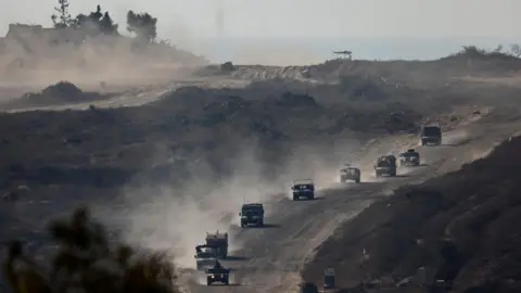 Reuters - Israëlische militaire voertuigen in de Gazastrook, gezien vanuit Israël (14 augustus 2024)