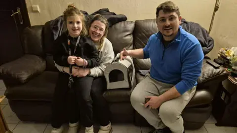 Family handout Rudolf Szentimrey with his wife Anita, seven-year-old daughter Noemi and kitten Mancs who is in a basket, at their home.