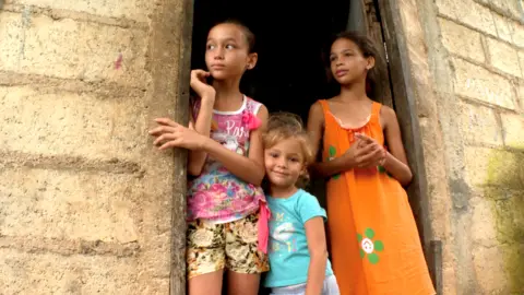 Three children stand in a doorway