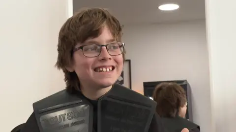 A young boy in glasses sitting in a hairdresser's chair