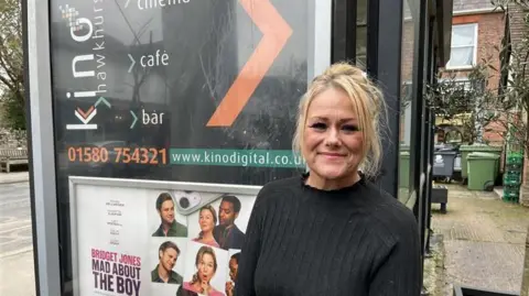 Phil Harrison/BBC General manager of The Kino in Hawkhurst, Donna Taylor, pictured in front of an advertisement for the venue. A trailer picture for the latest Bridget Jones film is included as part of the advertisement.