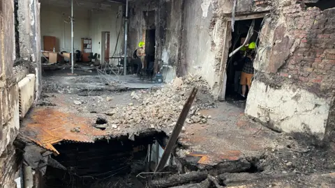 Journalists are shown the destroyed top floor of Ukraine's main government building in Kyiv, following a Russian air strike