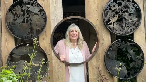 Woman puts her head through a hole in a large bird house structure