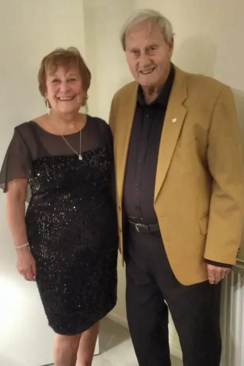 Beryl Powell Beryl Powell standing next to Roy Wood. She is wearing a sparkly black dress with short chiffon sleeves while Roy is wearing a mustard blazer, dark shirt and black trousers. Both are smiling.