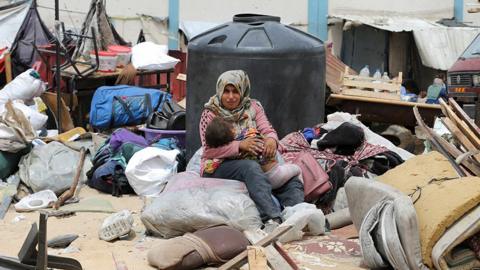 A woman and child sit amongst belongings in Rafah on 28 May