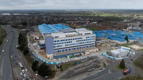 University Hospitals Dorset An aerial photo of Royal Bournemouth Hospital, a site with multiple buildings with blue roofs. Part of it looks to be a construction site