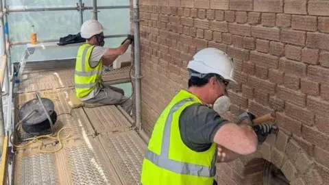 SK CONSERVATION Two workers inside the Faringdon Folly carrying out repairs. They are wearing face masks and helmets. 