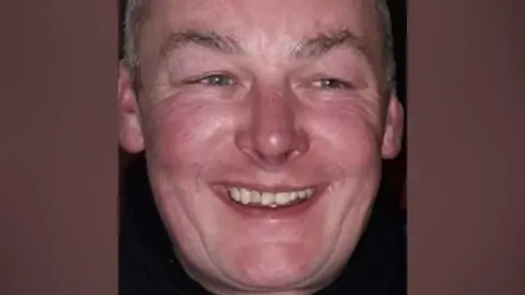Police Scotland Police handout image, close up of middle age man's face, smiling with red cheeks and crooked teeth