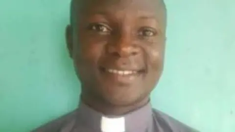 Fr Deusdedit Ssekabira in a grey shirt and white priestly collar