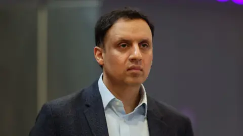 Getty Images Anas Sarwar has black hair and is wearing a dark suit and white open-necked shirt