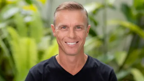 Troy Hunt A head shot of Troy Hunt who has short blonde hair and is wearing a black t-shirt