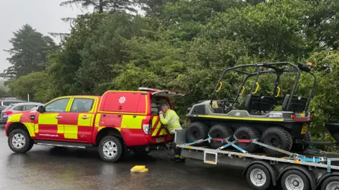 All terrain vehicle on a trailer being pulled by a Devon and Somerset Fire and Rescue Service 4x4