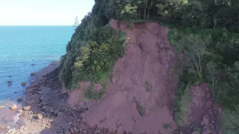 A drone picture of a cliff fall at Shaldon in Devon. Part of the cliff has collapsed with dirt and rocks scattered all over the beach. 