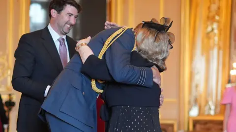 A close-up of Wendy Daunt in an embrace with the Prince of Wales at Windsor Castle during an OBE ceremony. 
