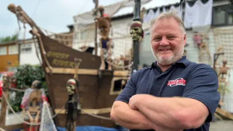 Stuart Woodward/BBC Lee Whitehair from Leigh-on-Sea standing in front of a Halloween pirate ship