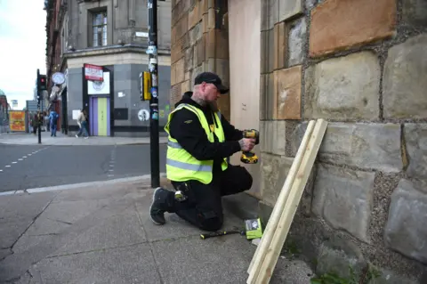 James Chapelard A workman boards up the entrance to Glasgow's historic Mercat Cross
