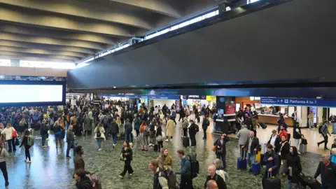 PA Media The passenger concourse at Euston station, busy with travellers moving in all directions. A huge screen hangs above running the length of the concourse. The screen is blank. 