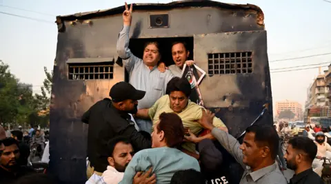 AFP via Getty Images Policemen detain Pakistan Tehreek-e-Insaf (PTI) party supporters during a protest against the 27th constitutional amendment, in Karachi on November 21, 2025.