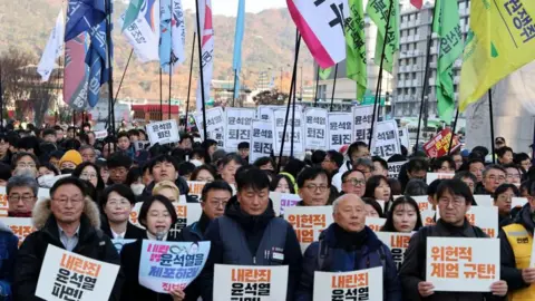 EPA Protesters hold placards and flags during a demonstration calling for the dismissal and impeachment of South Korean President Yoon Suk Yeol outside the National Assembly in Seoul, South Korea, 04 December 2024