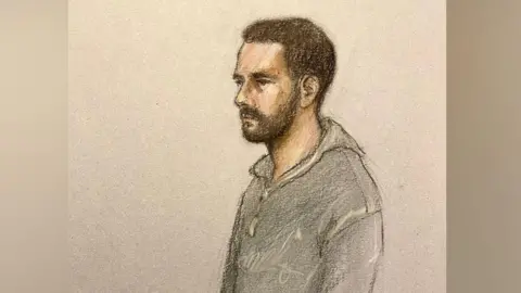 A court sketch of a man with a short black beard wearing a tracksuit standing in the dock of a courtroom.