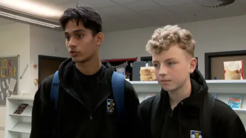 Two school children standing in a library