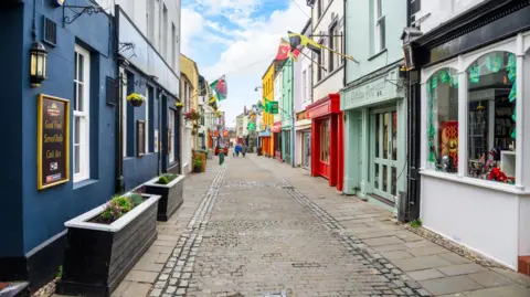 Getty Images A stock photograph of Palace Street on Caernarfon, showing cobbled streets and different coloured shop fronts featuring flags