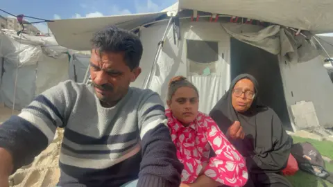 Sabrine al-Da'ma (R) gestures during an interview, with her daughter Rawa (C) and her husband beside her, in Gaza City, northern Gaza