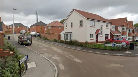 Google A junction at the end of a residential street. There are road signs that read "Martial Road" on either side of the junction, as well as houses on both sides too.