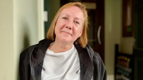 Restaurant supervisor Michelle Grierson, wearing a white top and black jacket, looking into the camera