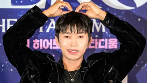 Lim Young-woong gestures a heart shape with both of his arms raised above his head