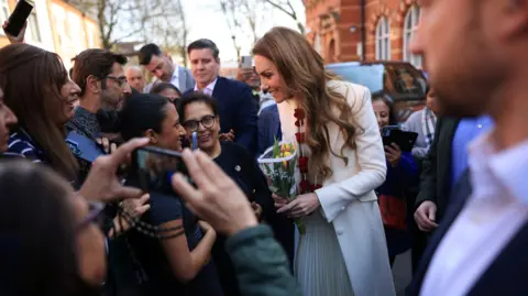 James Glossop/ The Times/ PA Wire Kate is speaking to people in a crowd while holding flowers