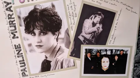 A scrapbook page with Pauline Murray's name drawn in bold letters down the left side of the page. There are three photos of Pauline Murray on the page, one a black and white portrait on the left, another black and white photo of her on stage singing into a microphone. Another shows her staring into the camera with four men standing behind her. 