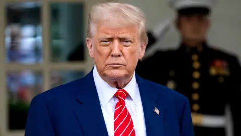 President Donald Trump in a dark suit and red tie 
