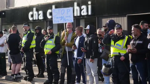 Protesters standing outside shop called 'Cha Cha Chai'.