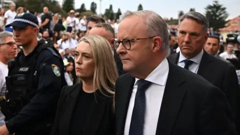 EPA A grey-haired man in a dark suit and tie and a blond haired woman in dark clothing in a crowd of people.