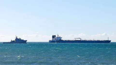 A French navy boat in the sea next to the Grinch oil tanker