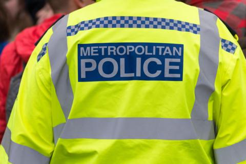 Image of the back of a police officer wearing a jacket which reads: "Metropolitan Police". 