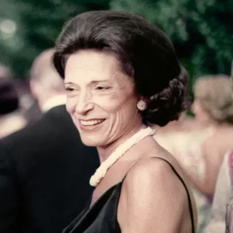 Courtesy Gap Inc A smiling middle-aged Doris Fisher, with dark brown hair. a white thick necklace, and a black thin strapped dress