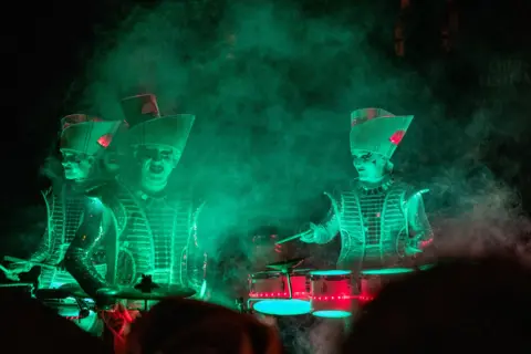 Threee illuminated drummers playing during a halloween festival