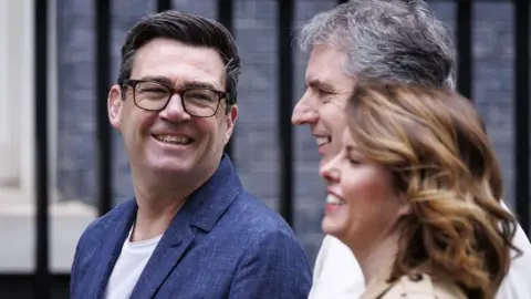 EPA Prime Minister Andy Burnham smiles alongside Mayor of the Liverpool City Region Steve Rotherham and Mayor of North East Kim McGuinness 