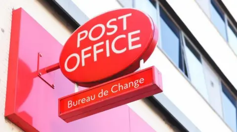 Getty Images Red Post Office sign, with Bureau de Change connected  a smaller motion   hanging underneath it