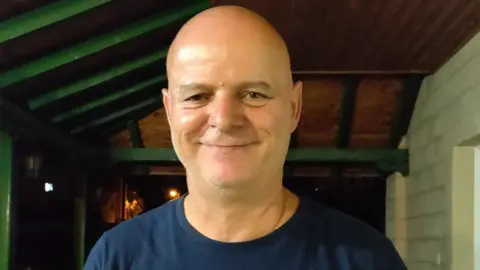 Staffordshire Police A bald man in a blue T-shirt smiles at the camera