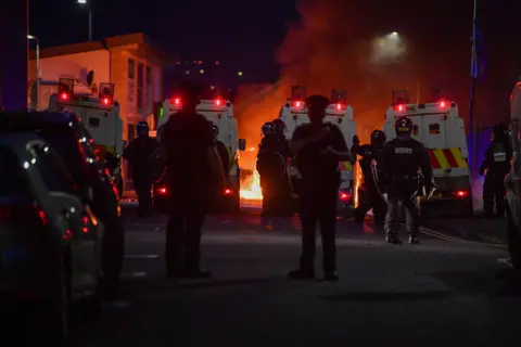 Pacemaker Riot police on Donegall Road with fire in background