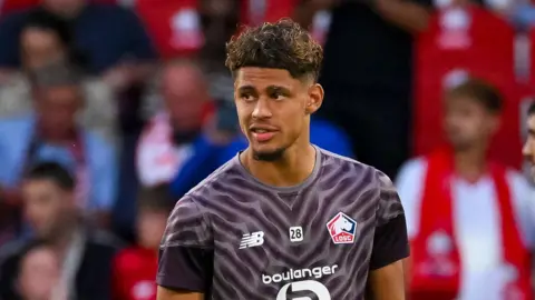 Ugo Raghouber with a number 28 in the middle of his chest, in between the Lille badge and the kit manufacturer's logo, warming up ahead of a match for the French club 