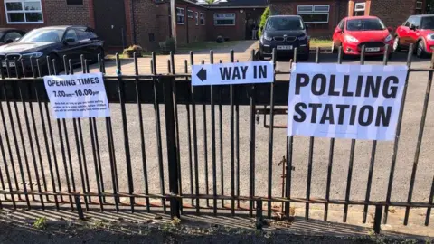 Signs on a school gate direct people to the polling station.